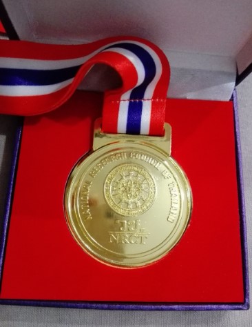 złoty medal w pudełku z czerwonym wykończeniem